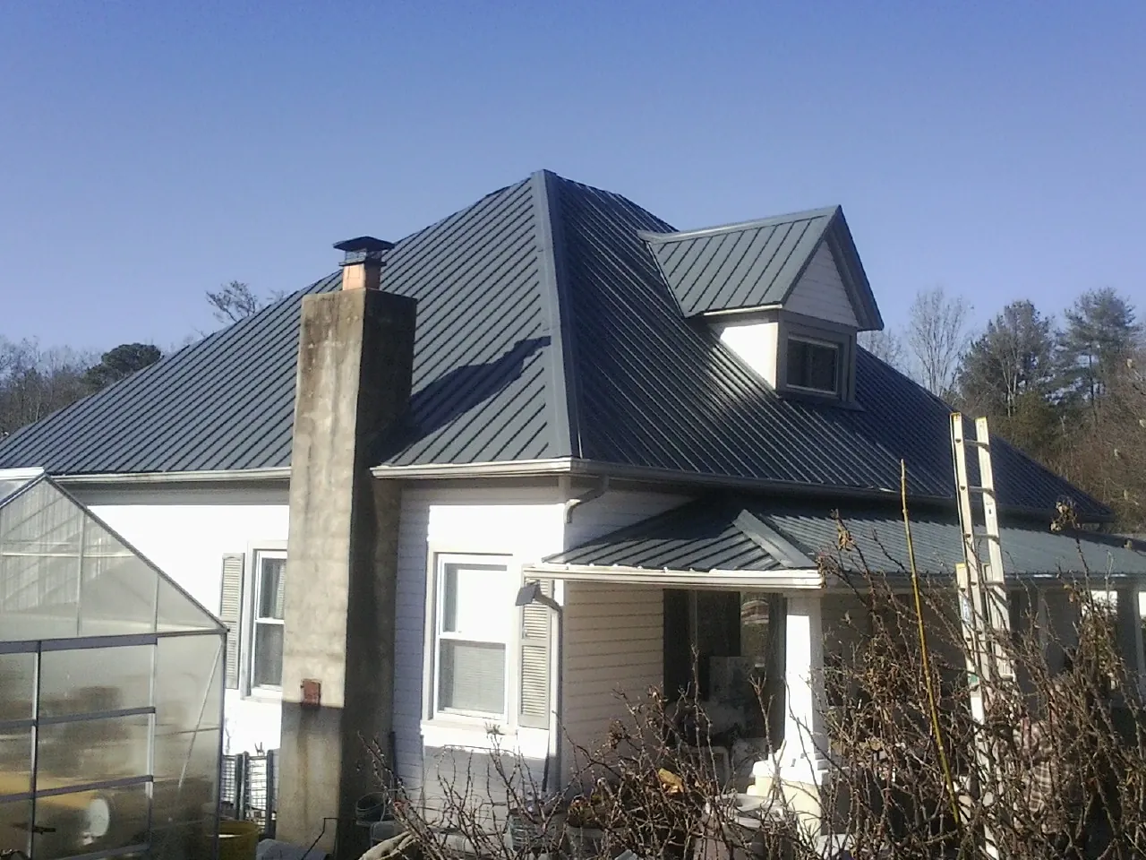 Dark blue standing seam metal roof on a white farmhouse with dormer — Slate & Tile Roof Repair by Roofing Brothers in Kathleen