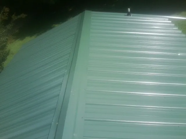 New green metal panels meeting at the ridge of a roof — Flat Roof Repair work by our crew in Kathleen