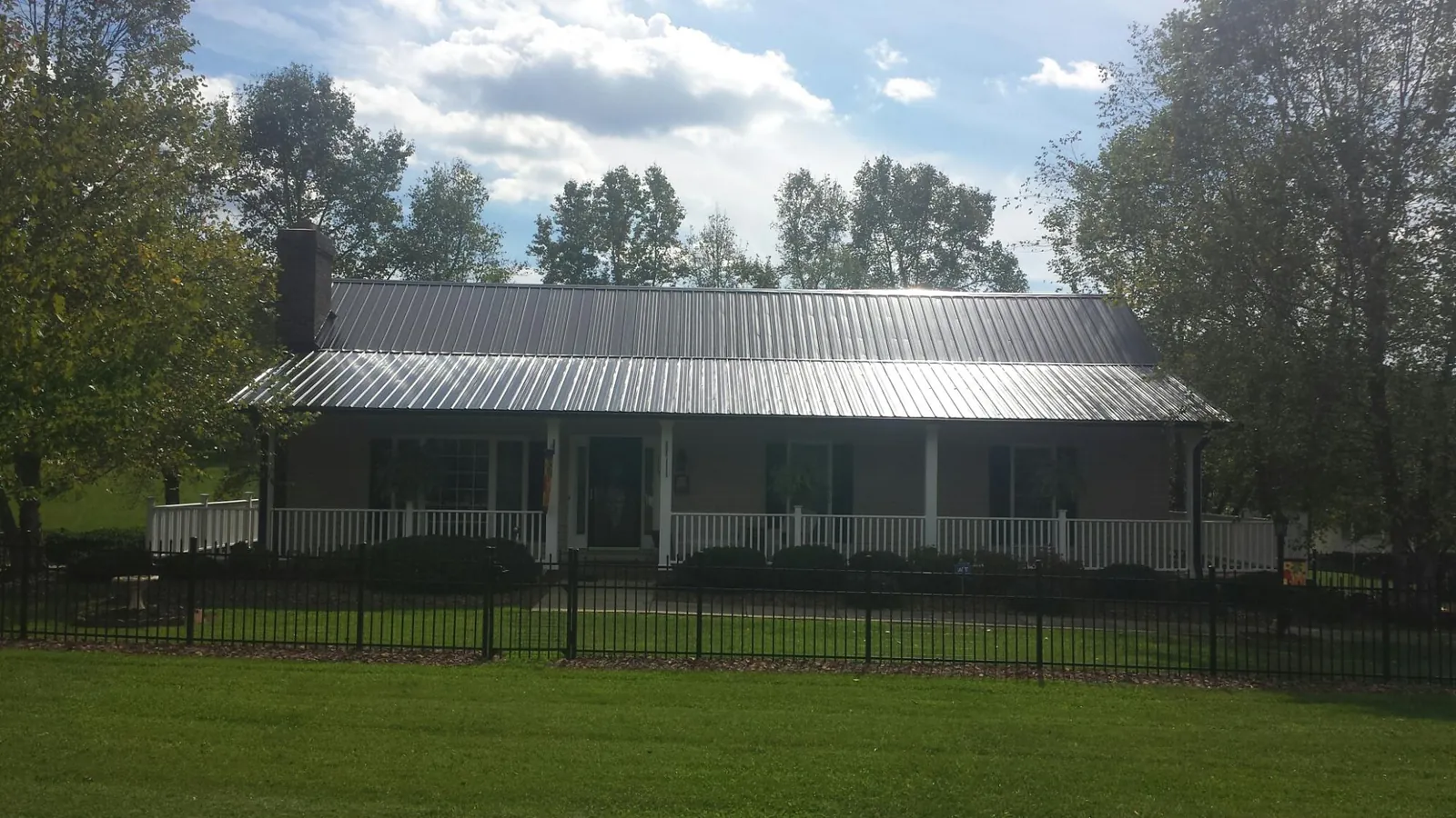 Gray metal roof on a brick ranch with a full width front porch — Gutter Guard Installation work by our crew in Kathleen