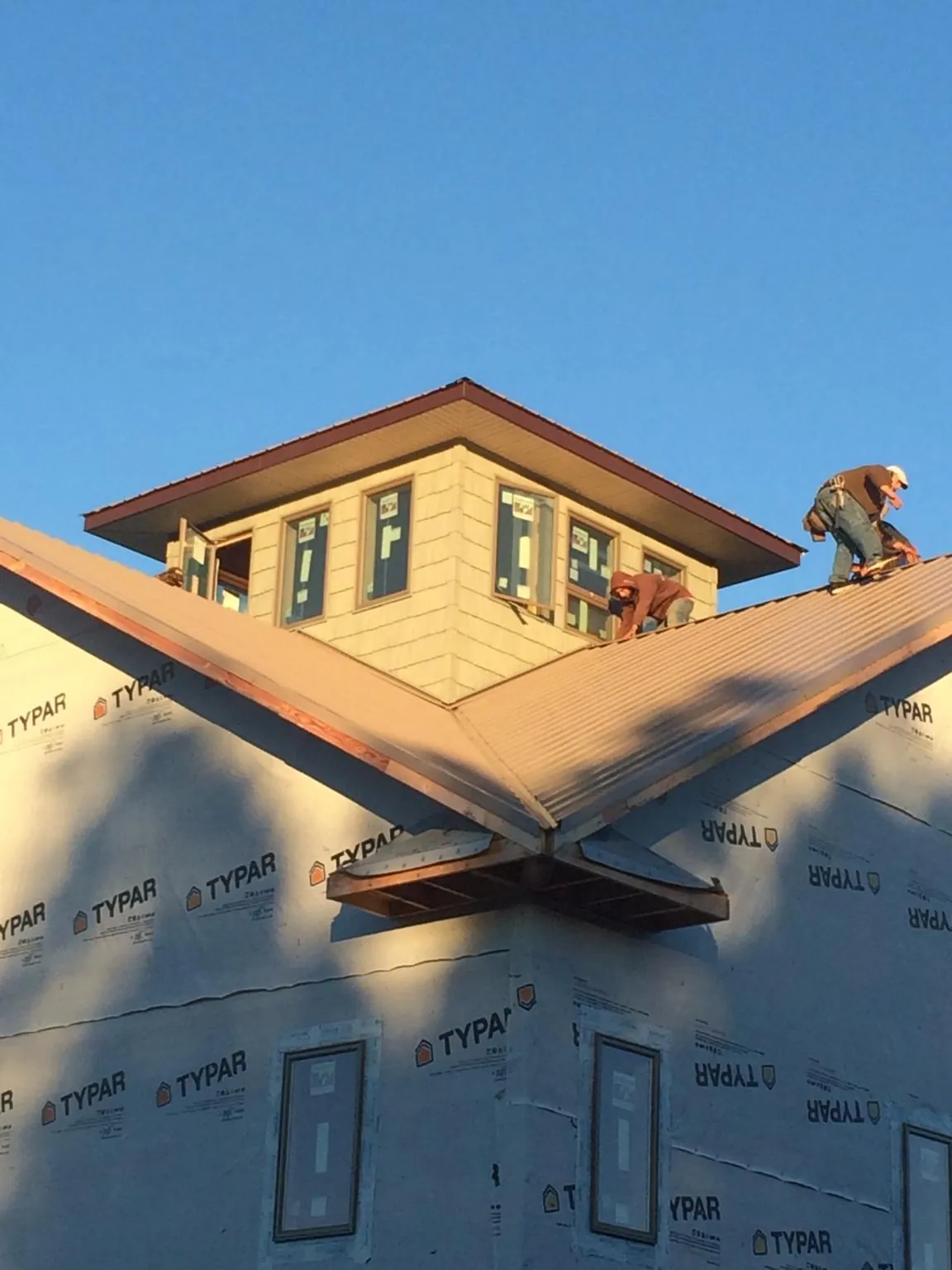 Roofers working around a rooftop cupola on a new metal roof at sunset — Roof Waterproofing in Kathleen by Roofing Brothers